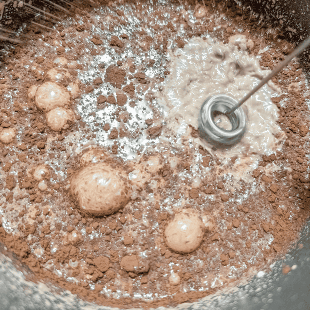 using milk frother to mix cocoa powder into half and half cream in saucepan