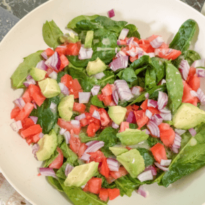 Healthy spinach salad with tomatoes, onions, and avocado for nutritious meals.