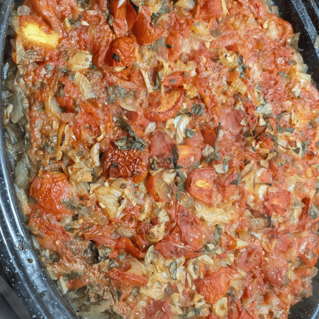 Homemade roasted tomato sauce with herbs and garlic in a baking dish.