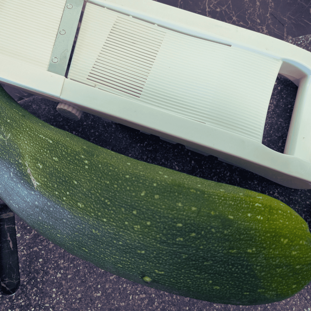 Fresh zucchini on a kitchen counter with a vegetable peeler.