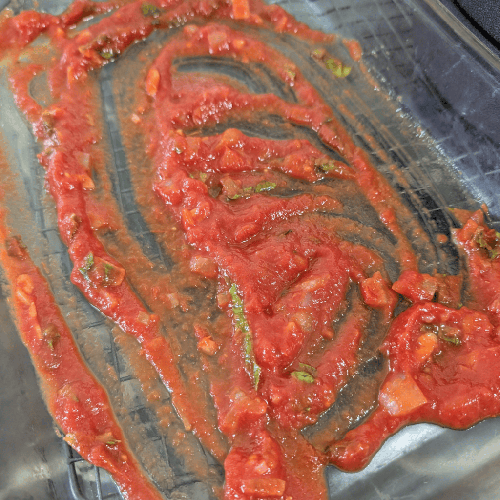 Close-up of homemade tomato sauce with herbs on a baking sheet.