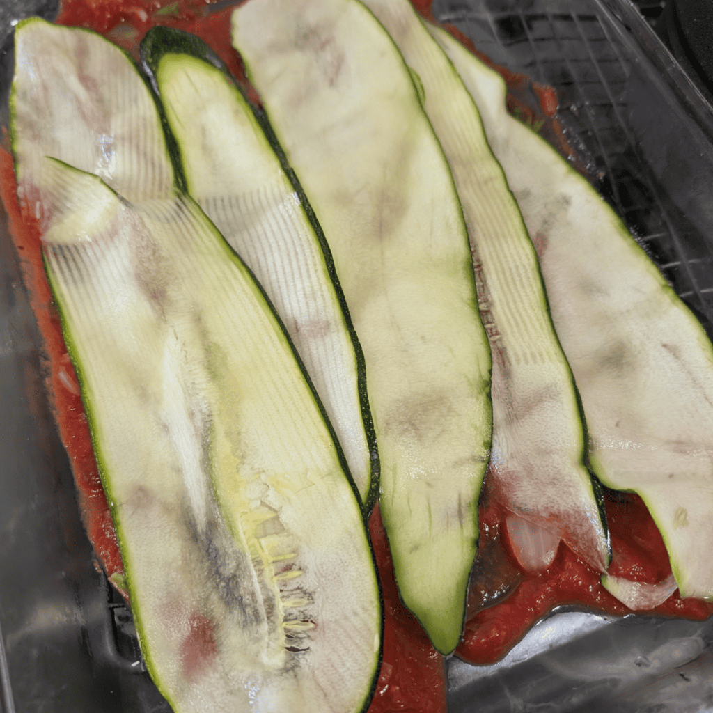Raw zucchini slices on a baking sheet ready for cooking or baking.