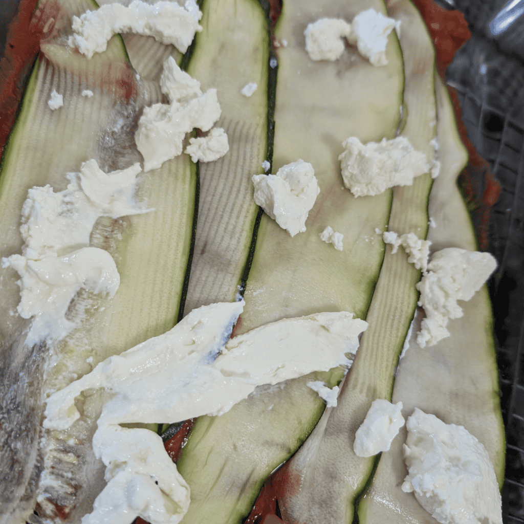 Fresh zucchini slices topped with cheese for cooking or recipes.