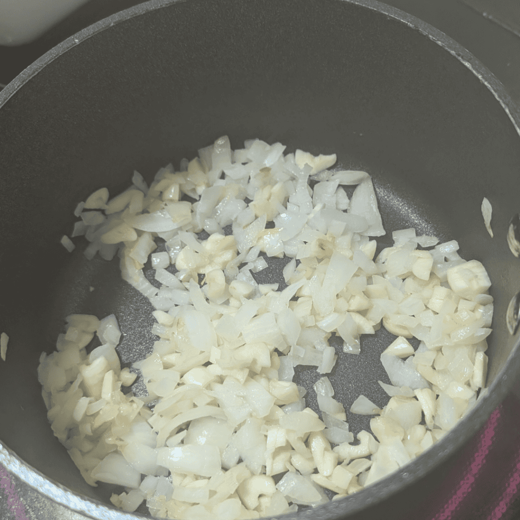 Chopped onions sautéing in a pan for zucchini lasagna recipe.