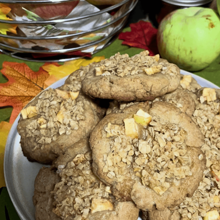 apple crisp cookies piled high on plate with fall decor and fallen apples in behind