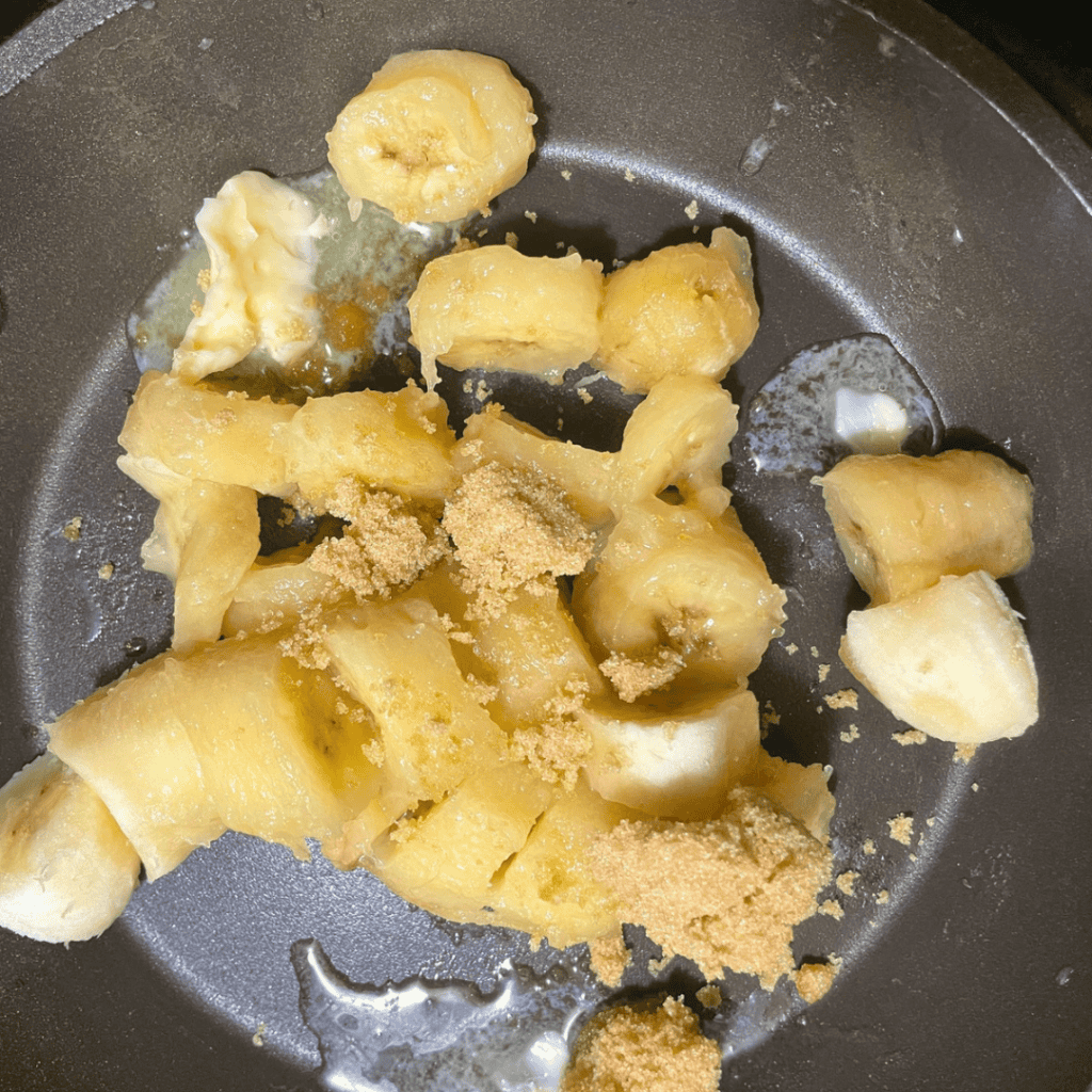 Close-up of banana chunks and brown sugar in a skillet for cinnamon rolls.