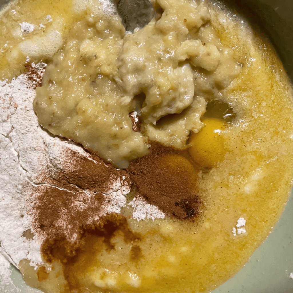 Mixing banana bread cinnamon roll ingredients with chocolate chips in a pan.