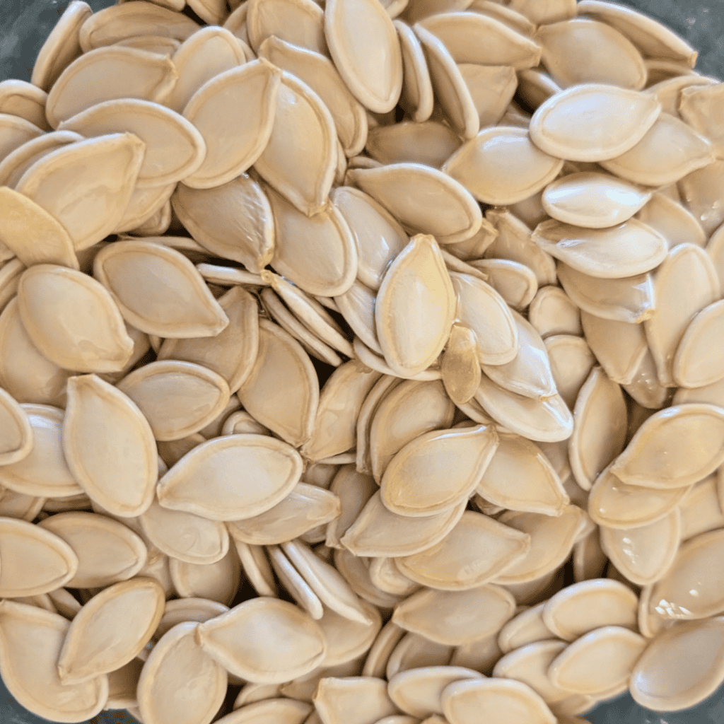 adding olive oil to pumpkin seeds