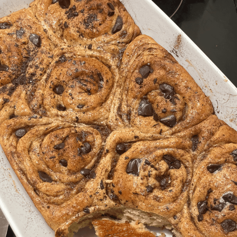 Freshly baked cinnamon rolls with chocolate chips in a baking dish.