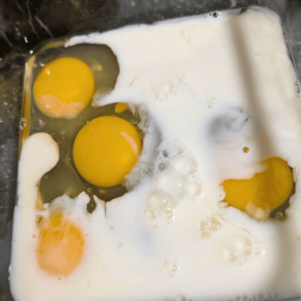 Eggs cracked into a pan for a farm-style vegetable omelet recipe.
