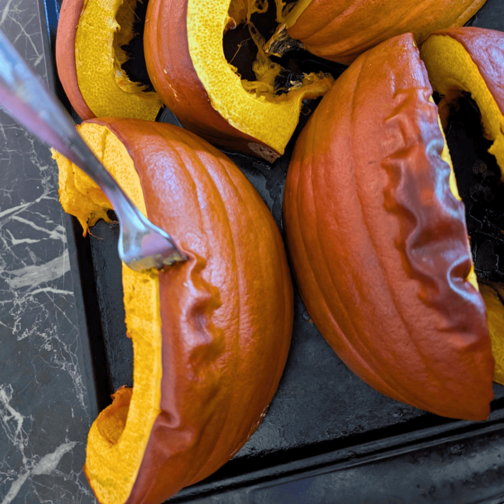 image of roasted pumpkin wedges on baking tray with fork sticking into one