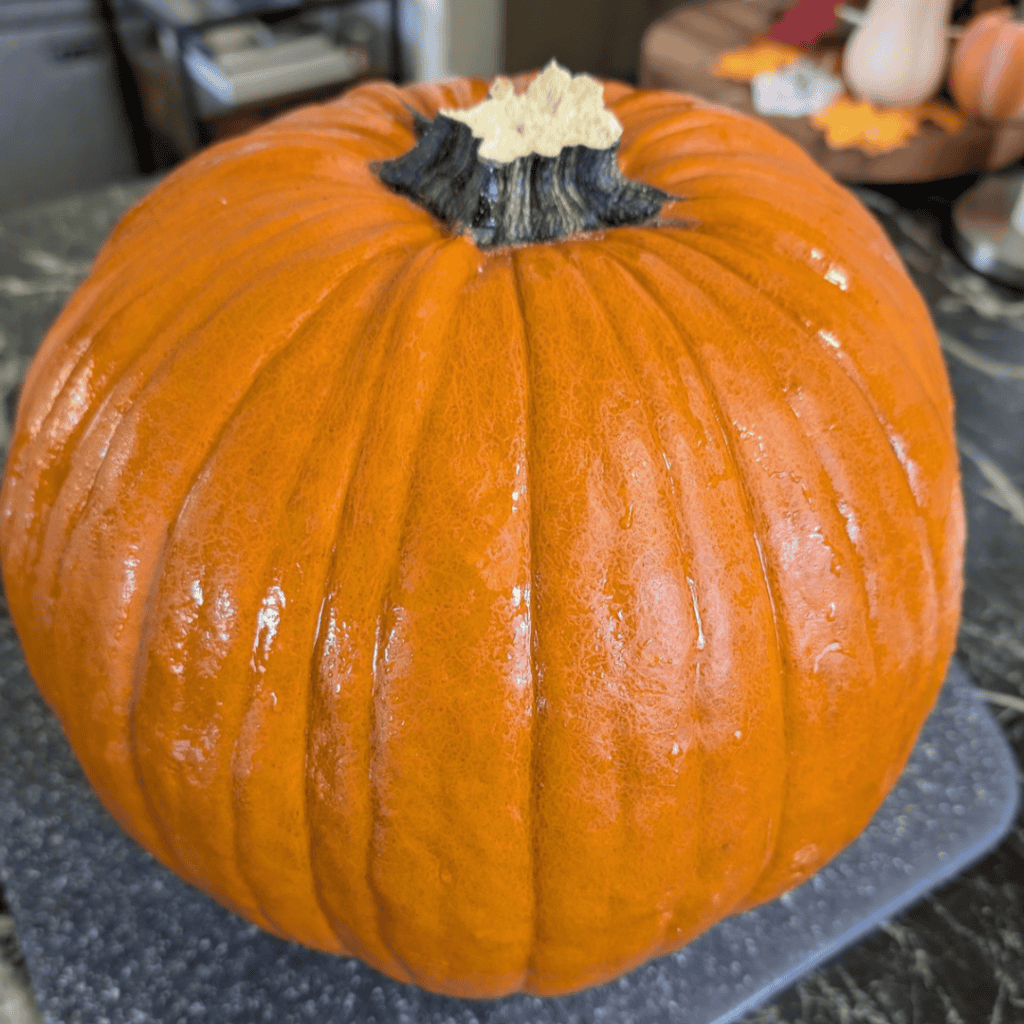 whole pumpkin sitting on table and cutting board