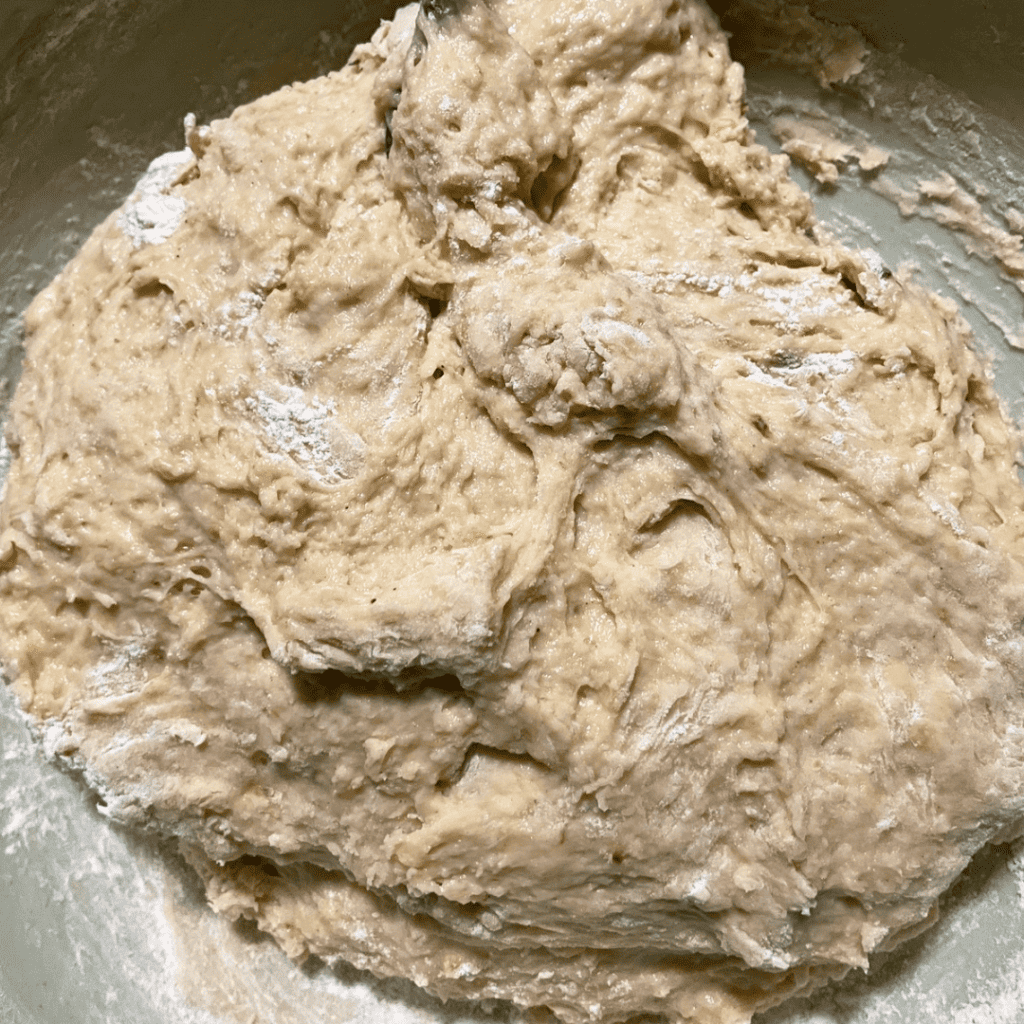 Creamy banana bread cinnamon roll dough with chocolate chips in a mixing bowl.
