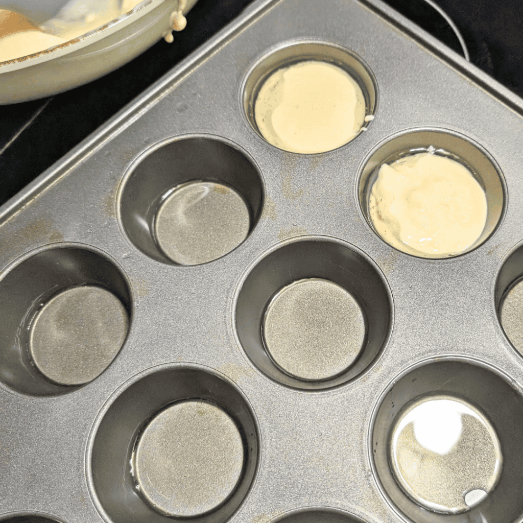 adding batter to oil in muffin tin