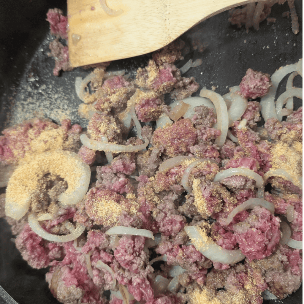adding garlic powder to beef with onion