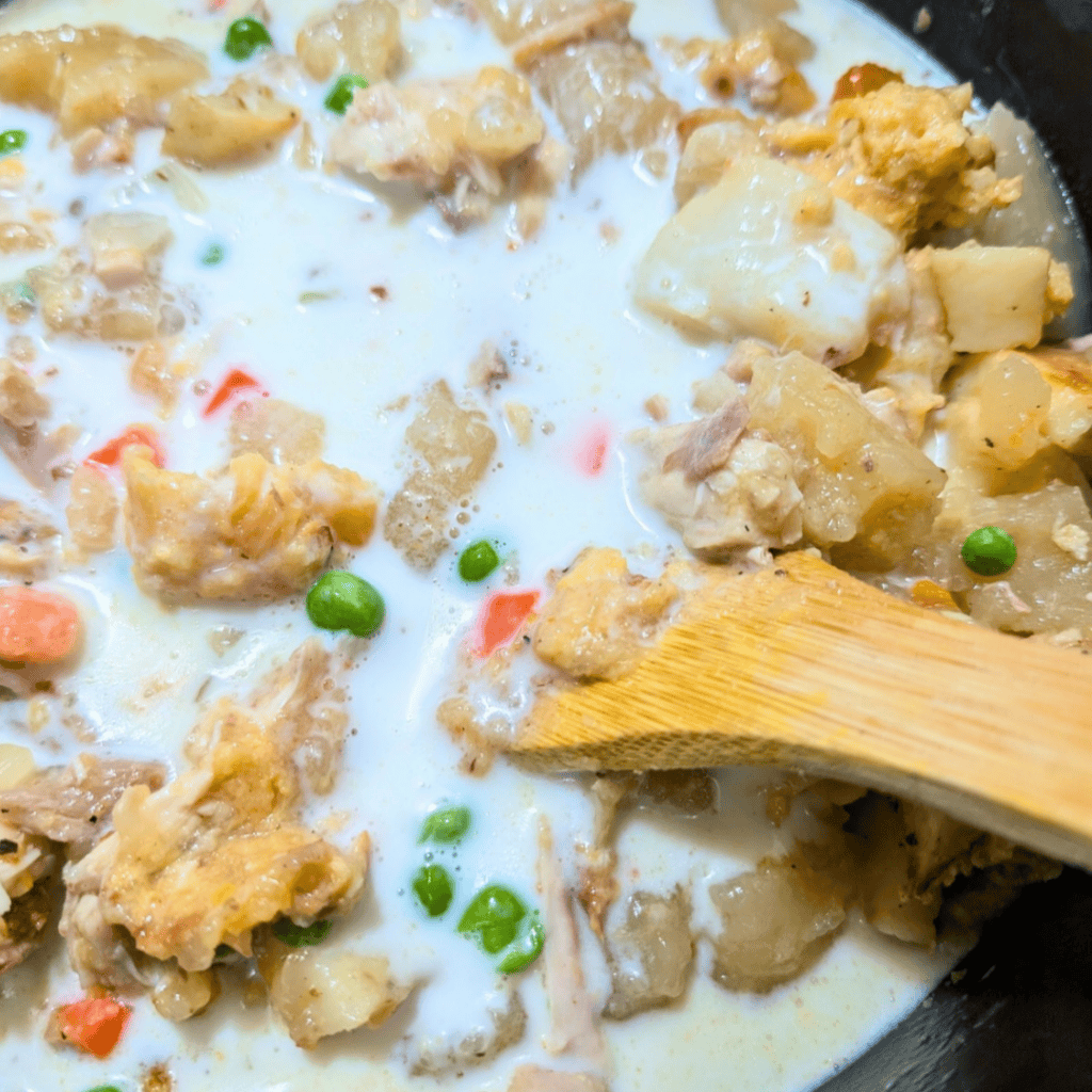 Creamy leftover turkey and dumplings with peas and vegetables in a skillet.