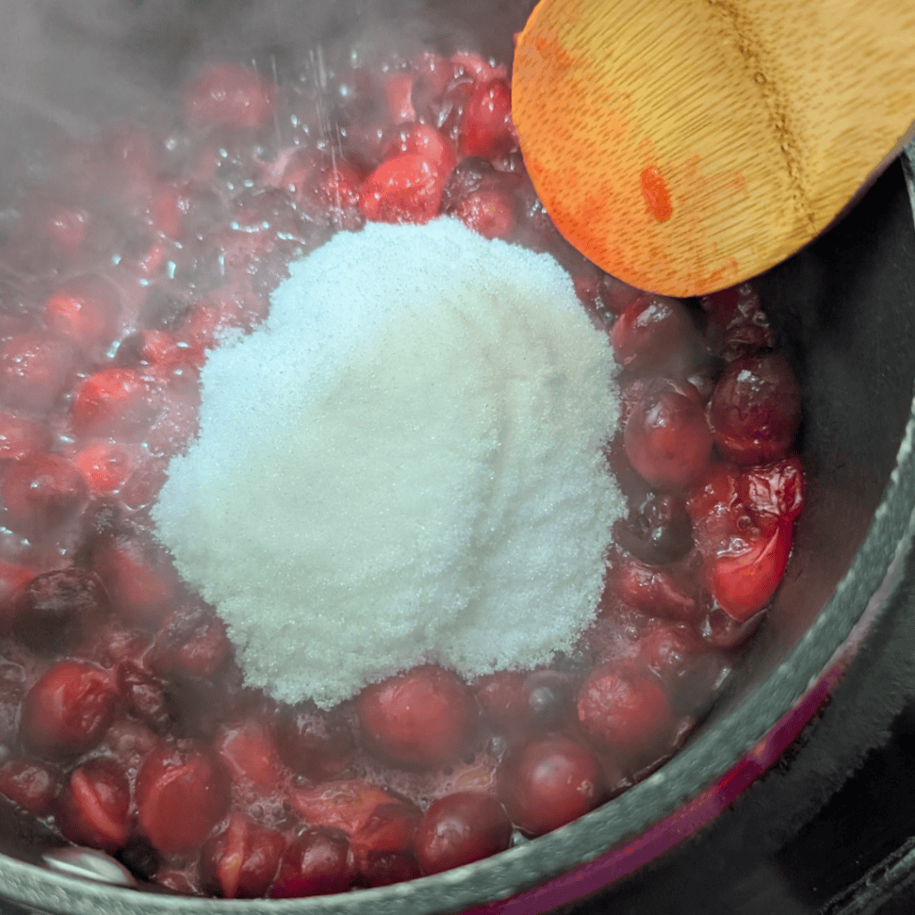 _adding sugar to cranberries in saucepan