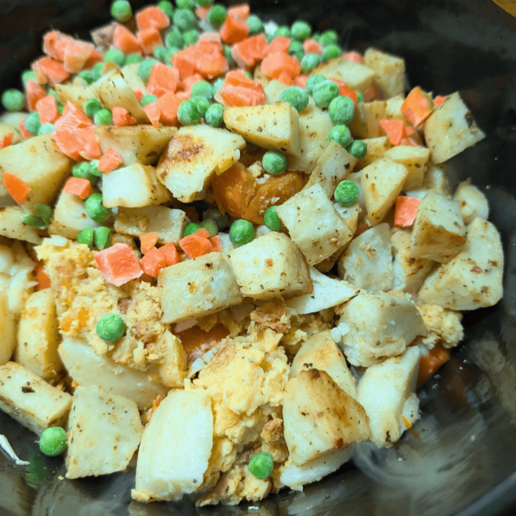Close-up of leftover turkey, dumplings, and vegetables in a skillet.