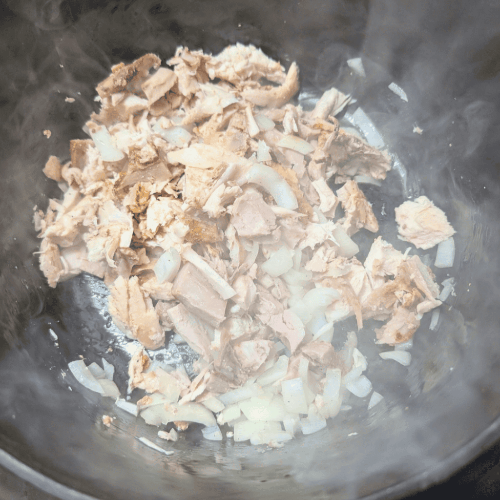 Leftover turkey and onions cooking in a pot for a recipe.