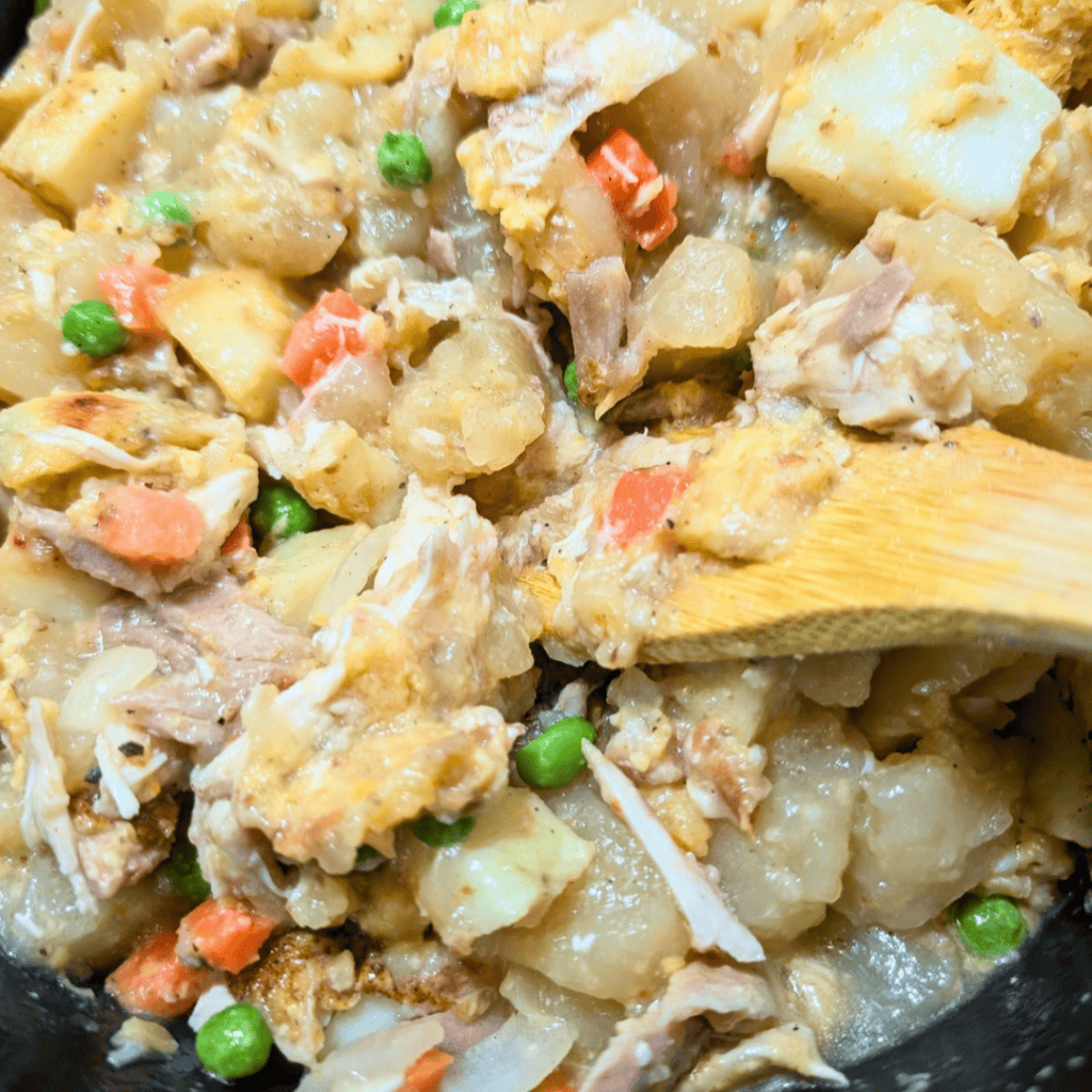 Hearty leftover turkey and dumplings in a skillet with vegetables.