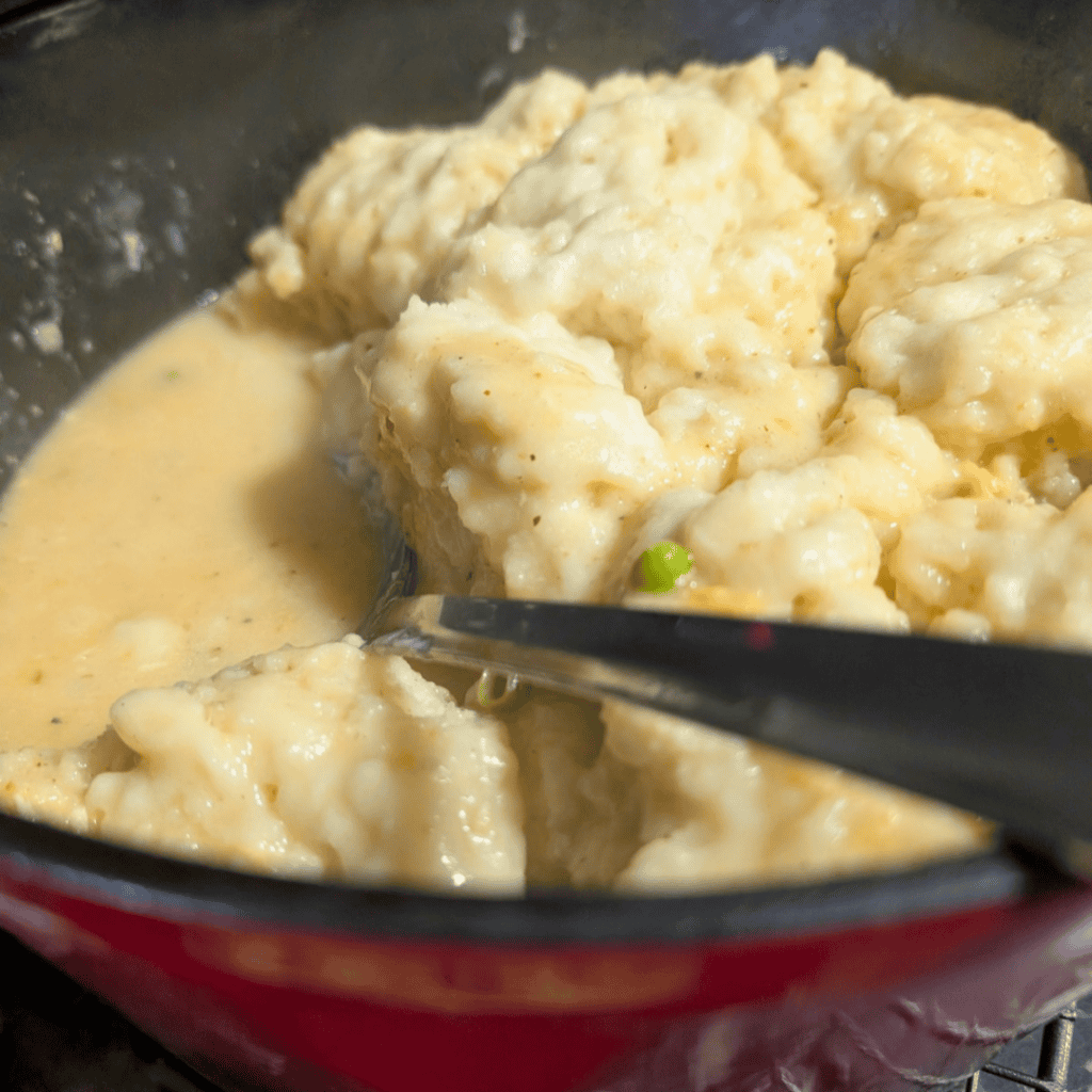 Creamy leftover turkey and dumplings in a pot with a spoon.