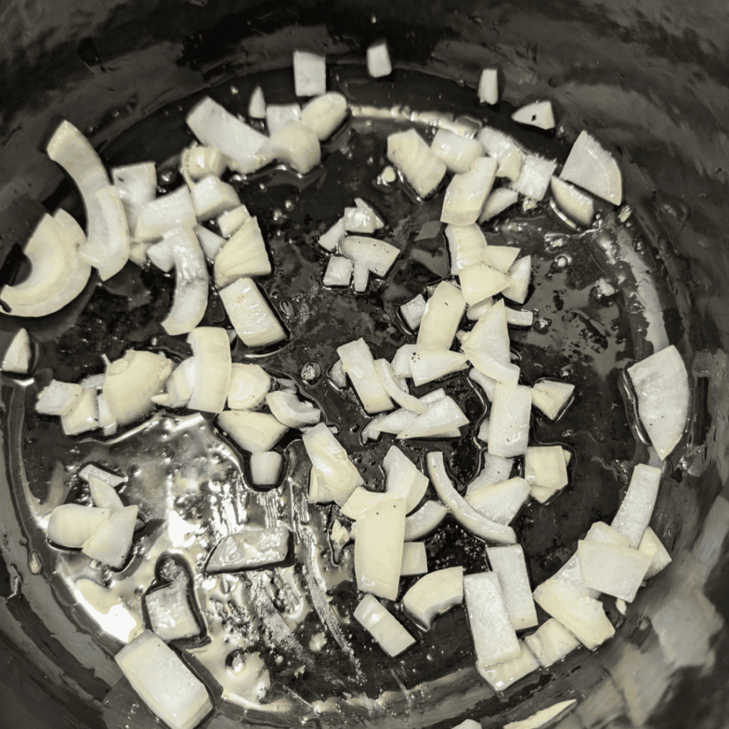 Chopped onions cooking in a skillet for turkey and dumplings recipe.