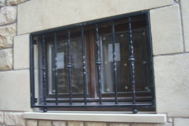 Reja de acero negra para protección de ventanas con barrotes y cristales resistentes.