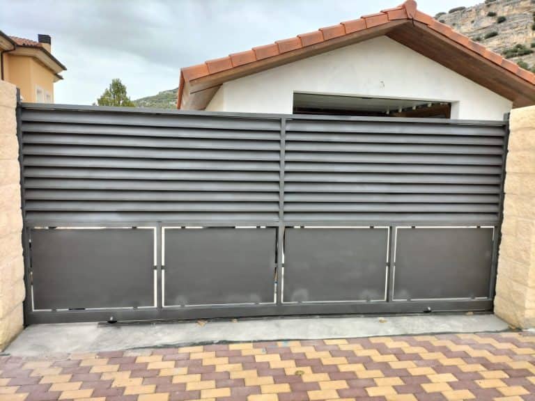 Puerta de garaje metálica automatizada en color gris y diseño moderno.
