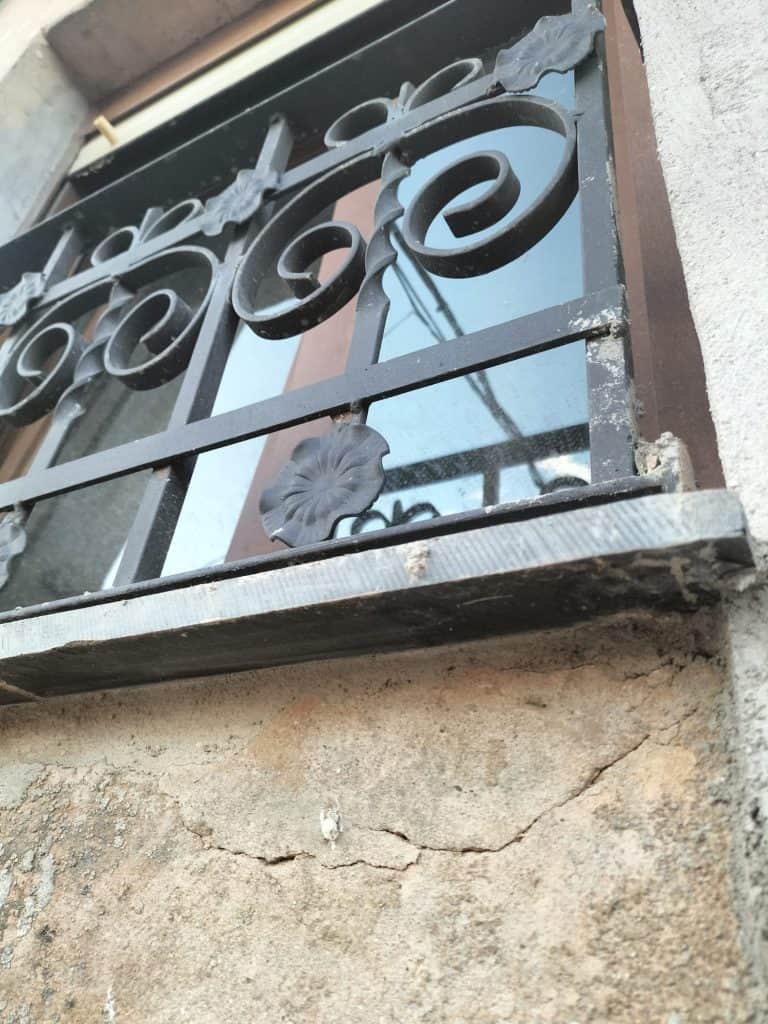 Reja de seguridad de hierro con diseño decorativo en una ventana, reparación y servicio de cerrajería.