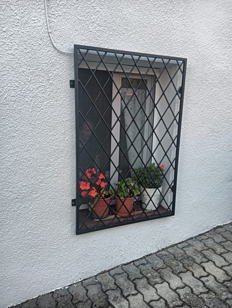 Reja negra de seguridad para ventana con plantas en macetas, protección y estilo.