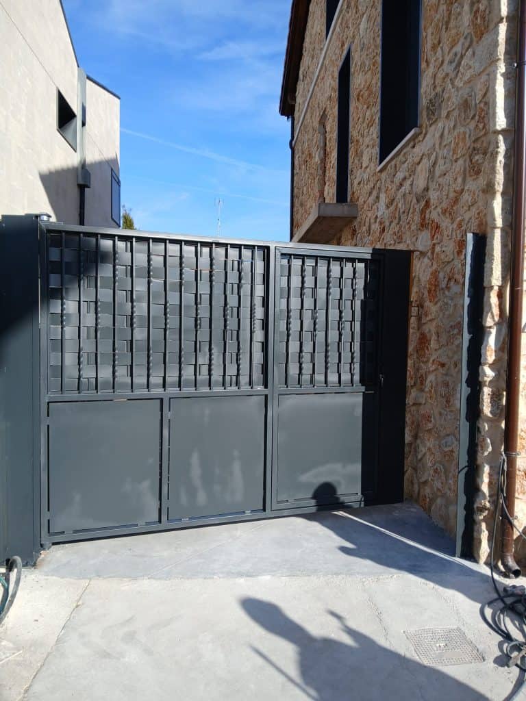 Puerta de seguridad de acero en color gris para entrada de vehículos.