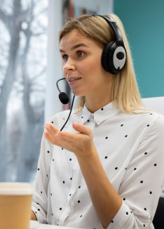 Customer service representative with headset and polka dot shirt at desk for enterprise cloud communications.
