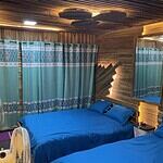 Cozy wooden cabin bedroom with blue bedding and patterned curtains for a relaxing stay.