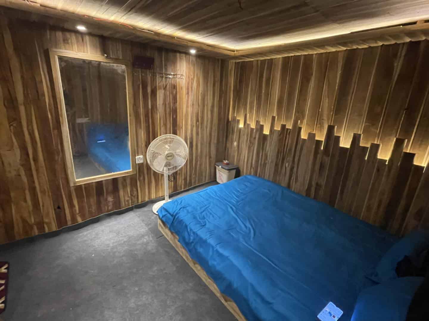 Cozy wooden bedroom with blue bedding and ambient lighting for a relaxing stay.