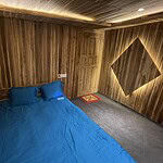 Cozy wooden cabin bedroom with blue bedding and ambient lighting, perfect for a relaxing stay.