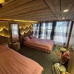 Cozy wooden cabin bedroom with two pink beds, warm lighting, and modern decor for a relaxing stay.