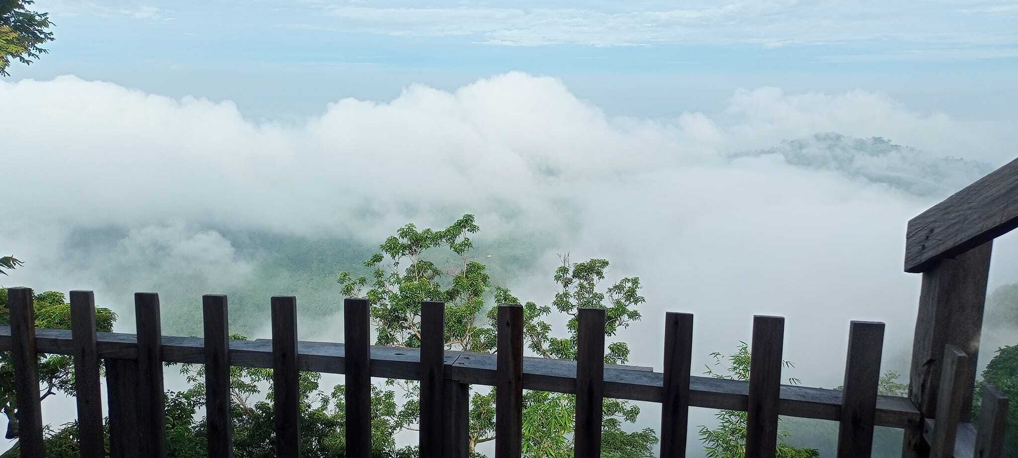 Mist-covered mountain view from a scenic lookout with wooden railing, perfect for nature and travel lovers.
