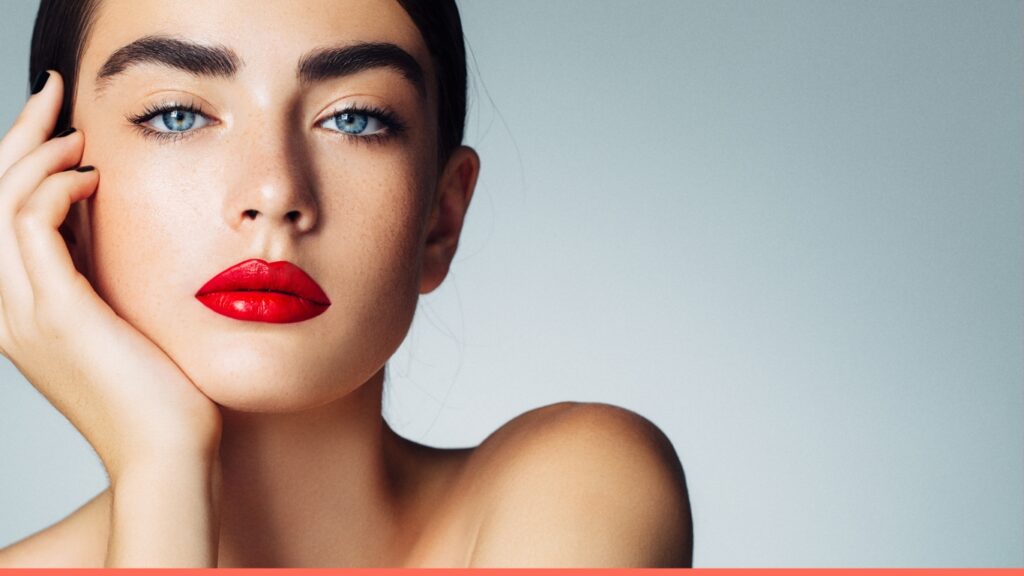 Close-up of a woman with bold red lips and flawless makeup for permanent makeup look.