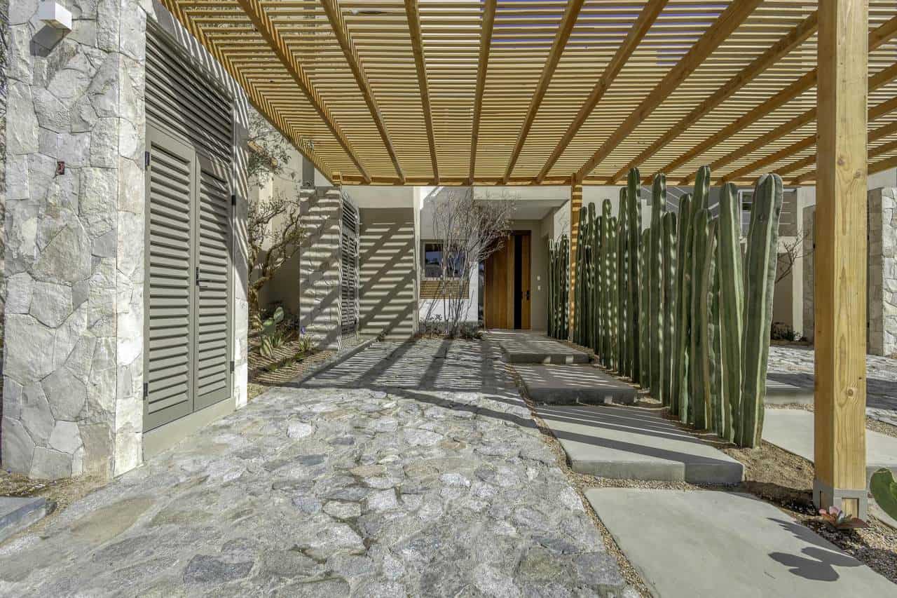 Modern Home Exterior With Wooden Pergola, Stone Pathway, And Tall Cacti Overlooking Golf Course And Ocean Views At Club Campestre.