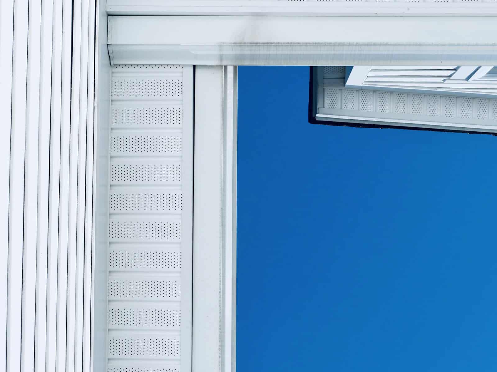 White vinyl siding, soffit venting and a weather stained gutter on a Cape Cod home, the surfaces a Pop-On siding maintenance routine cleans in salt air