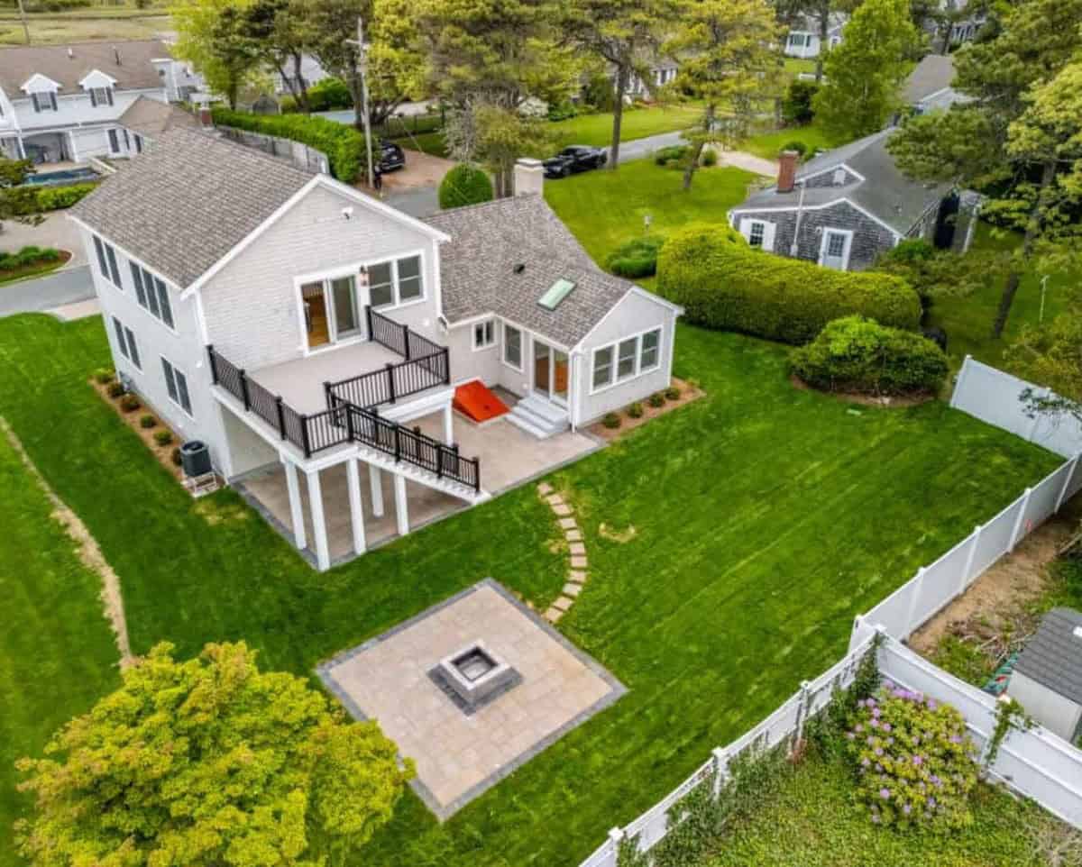Drone view of a finished Coast Carpentry Home Group project on Cape Cod with a new architectural shingle roof, skylight and brick chimney on a gray cedar shingle home