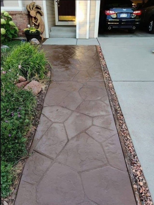 Brown flagstone‑pattern stamped concrete walkway leading to front door of a Colorado Springs home