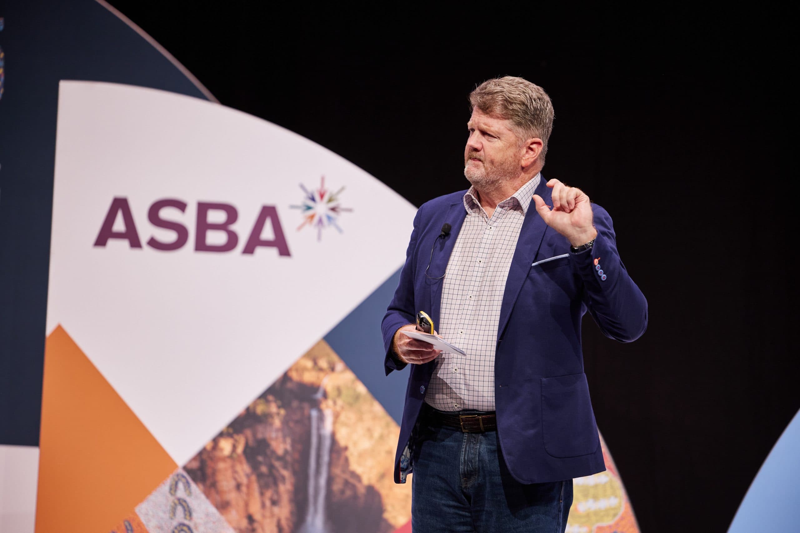 Gus McLachlan speaking on stage at an ASBA event