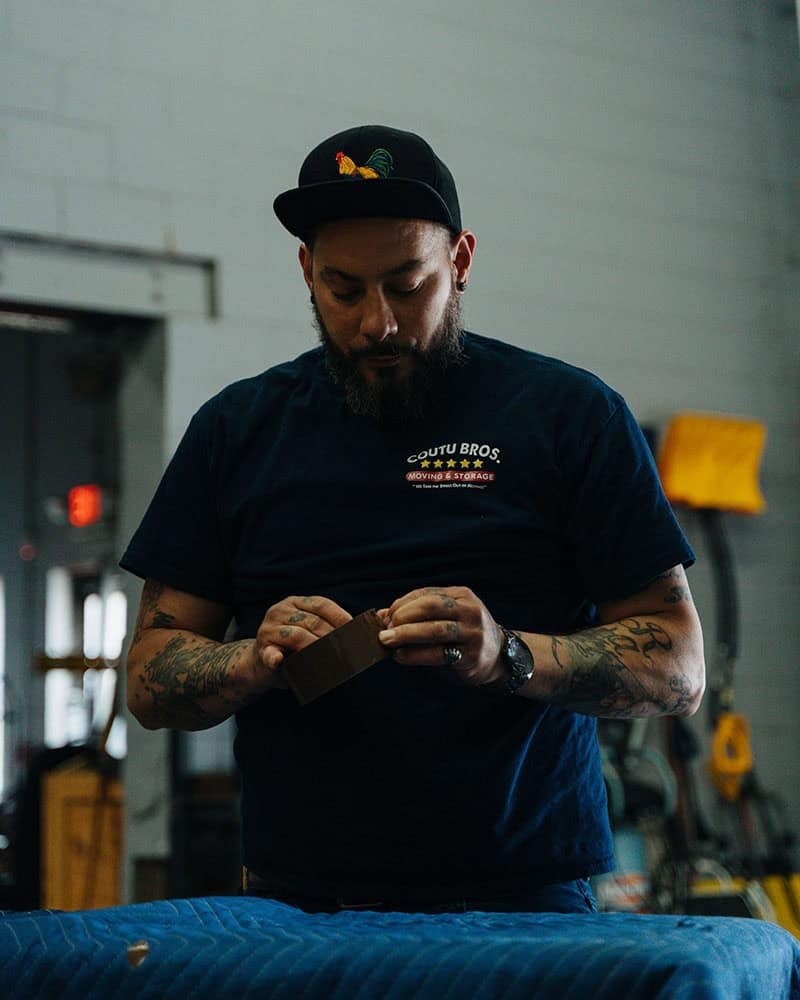 Coutu Bros. Moving & Storage employee inspecting a moving box in warehouse.