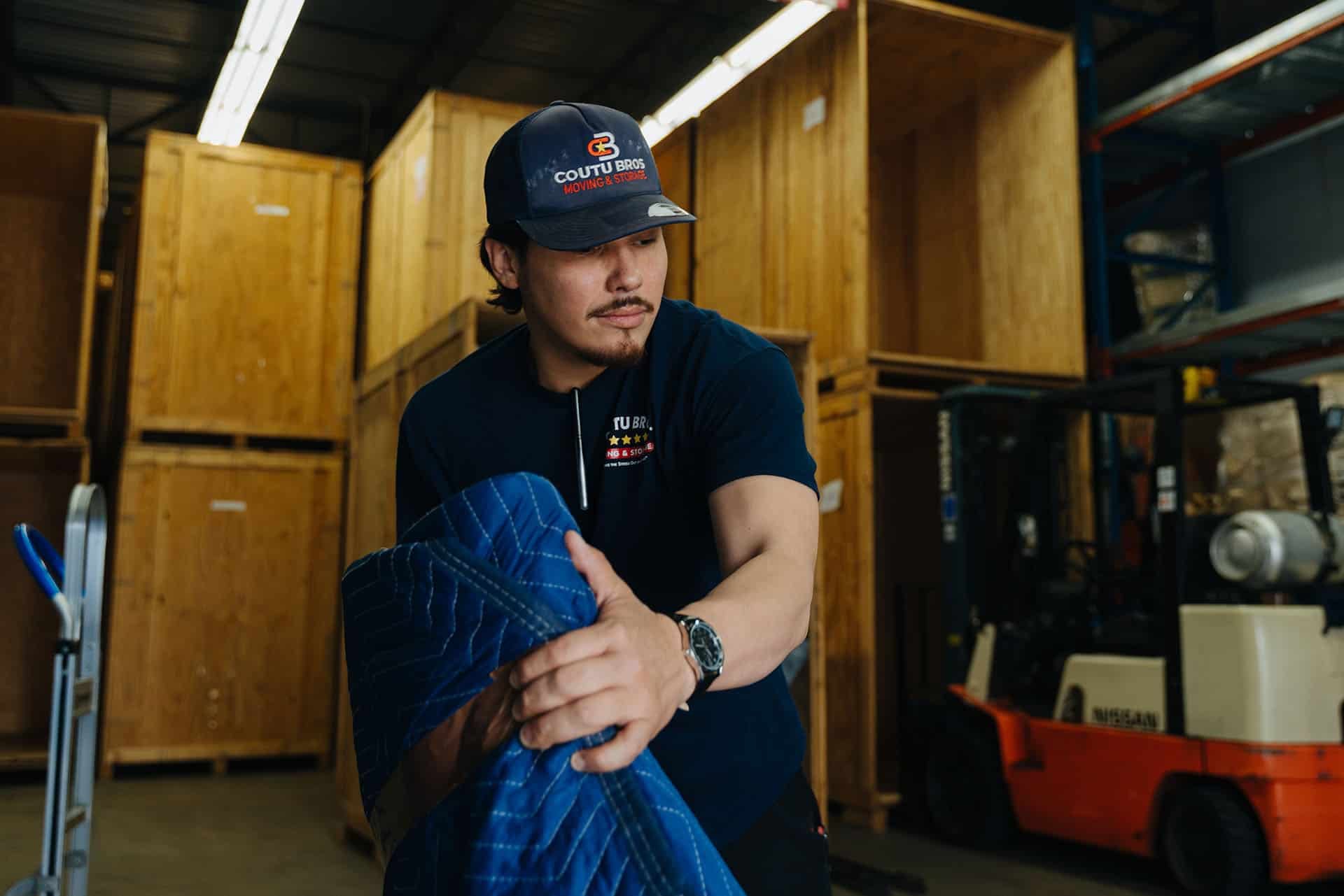 Coutu Bros. Moving & Storage employee preparing packing materials in warehouse.