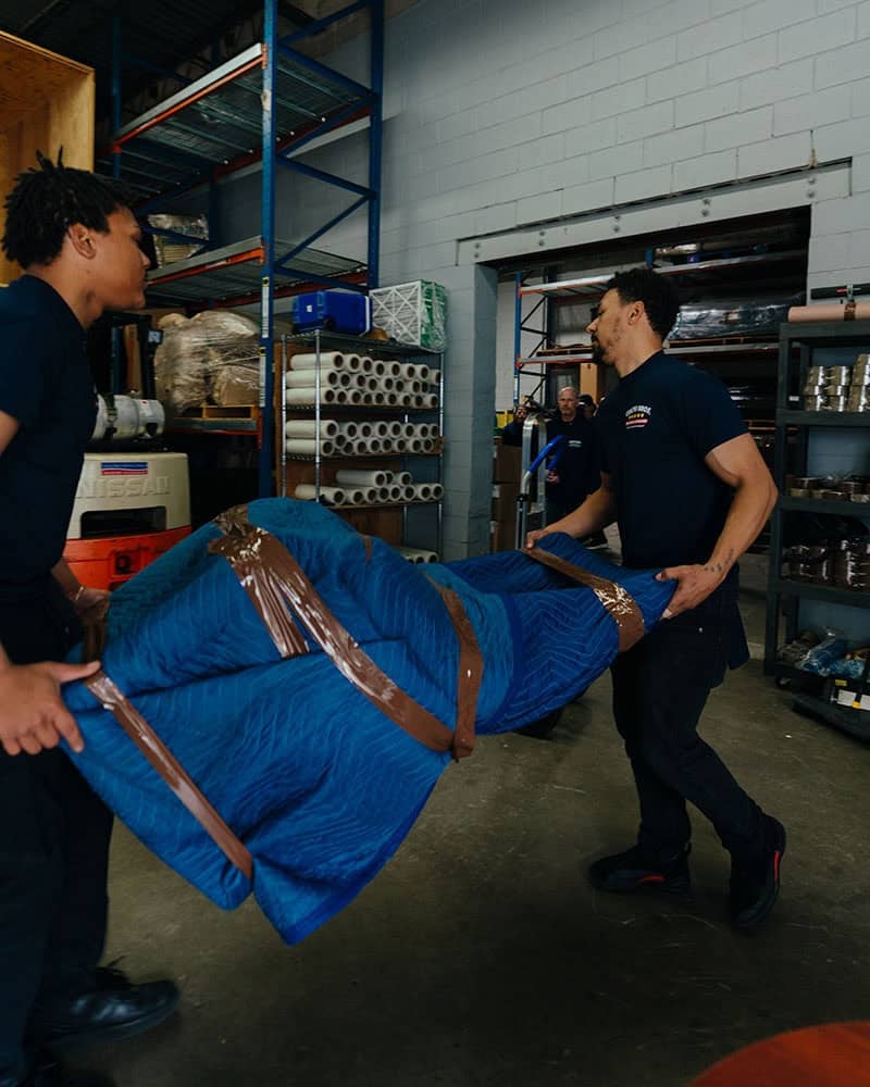 Coutu Bros. Moving & Storage team loading large packed item into warehouse.