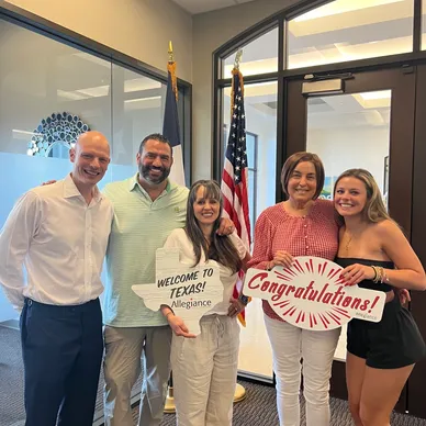 Group of five people celebrating with signs in an office.