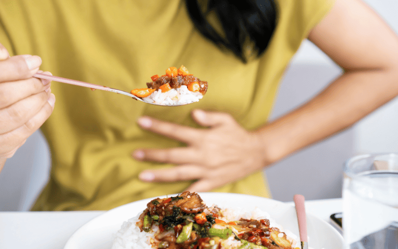 Person enjoying a healthy Asian rice bowl with vegetables and sauce.