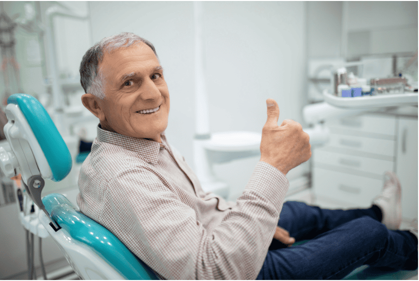 Smiling patient giving a thumbs-up while sitting in a dental chair