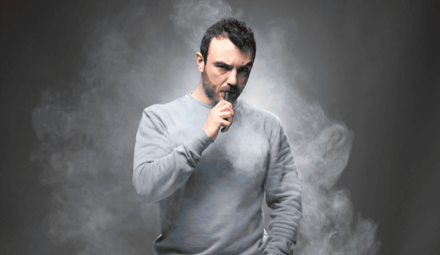 Man vaping in a cloud of smoke, highlighting the challenges of quitting vaping.